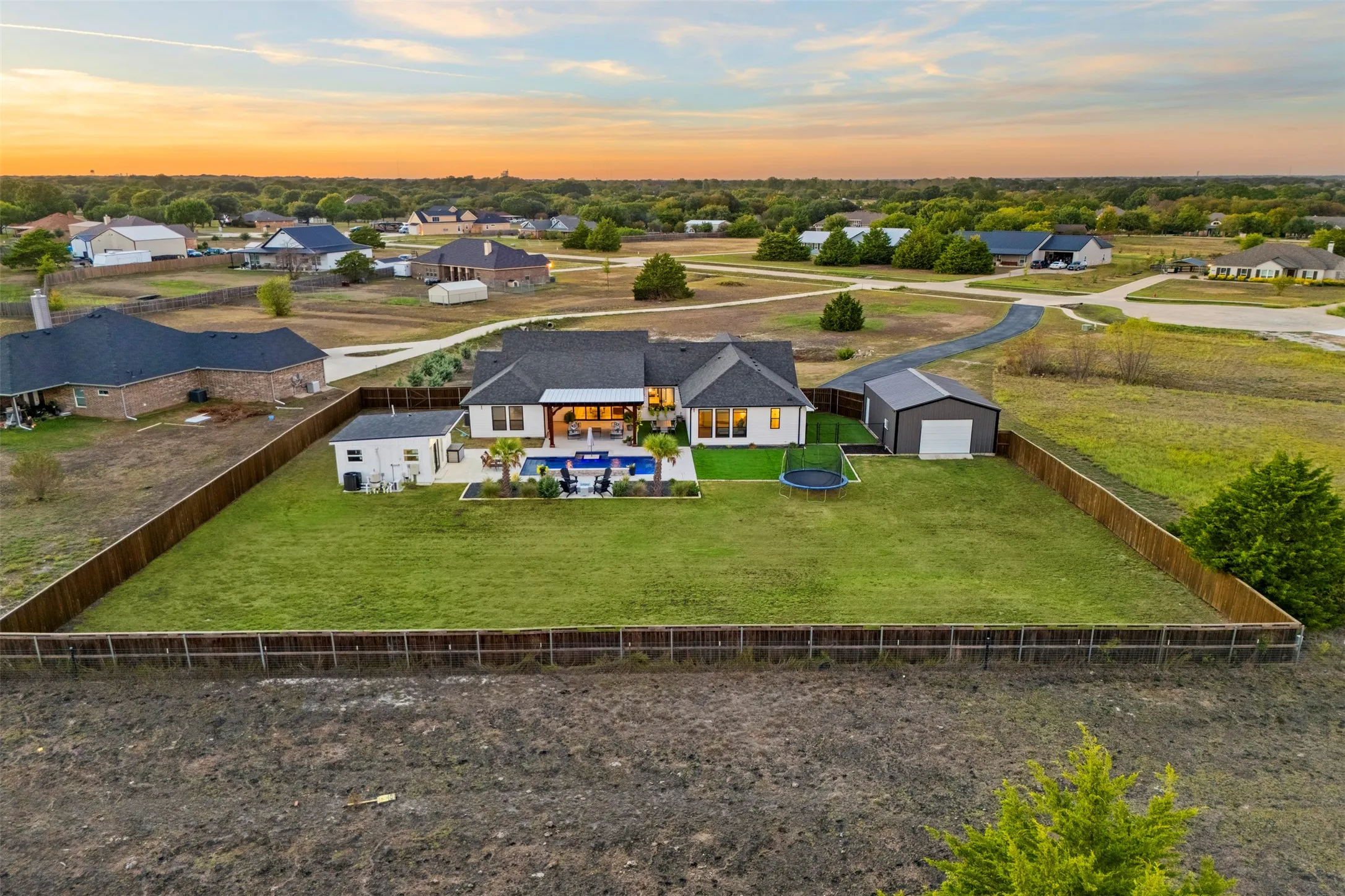 Aerial perspective shows the expansive fenced backyard and separation between the home, pool and shop.