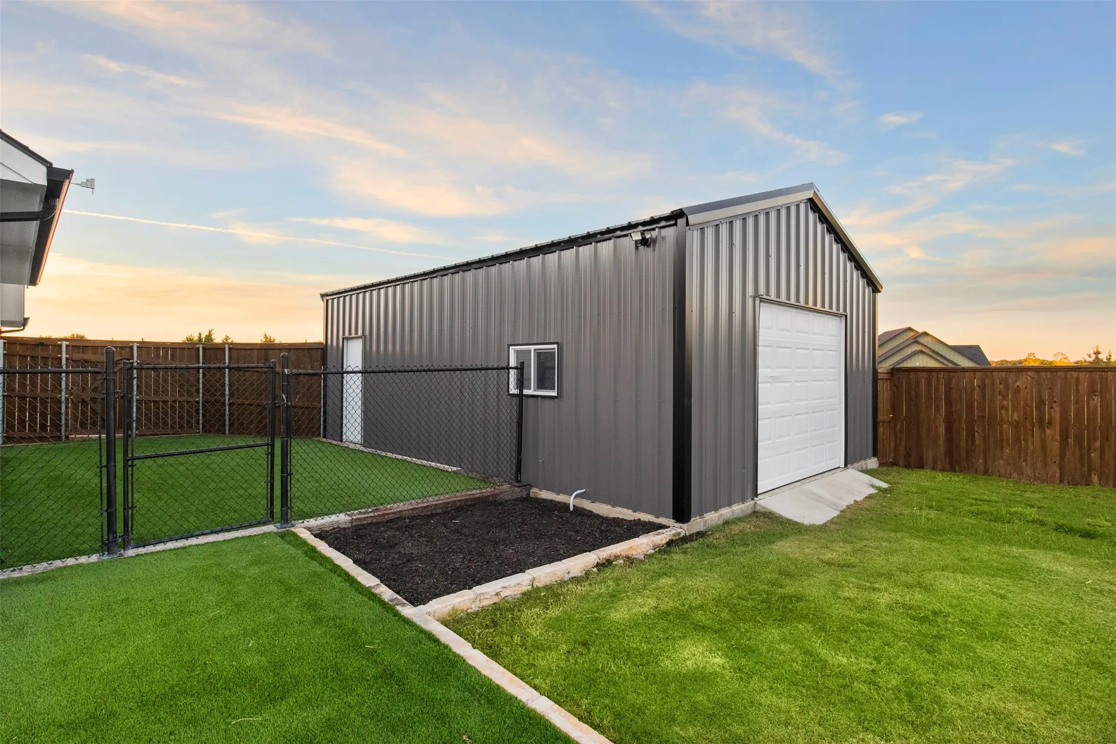 Separate 20×30 powered shop with roll-up doors at both ends. Next to separate fenced turfed side yard for pets or play