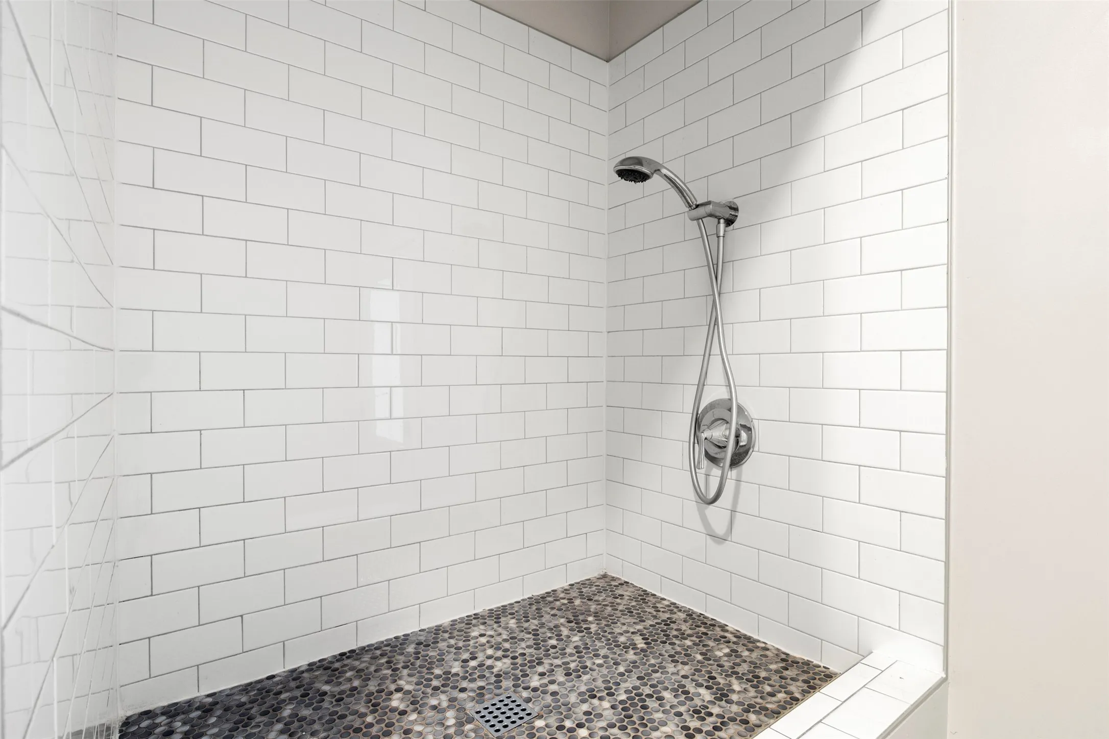 Elevated tiled pet-wash station with handheld sprayer and built-in niche.