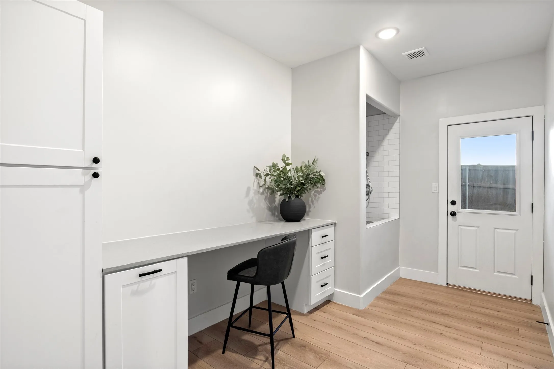 Built-in counter and cabinetry provide a convenient everyday workspace. Peep the wash station by the door.