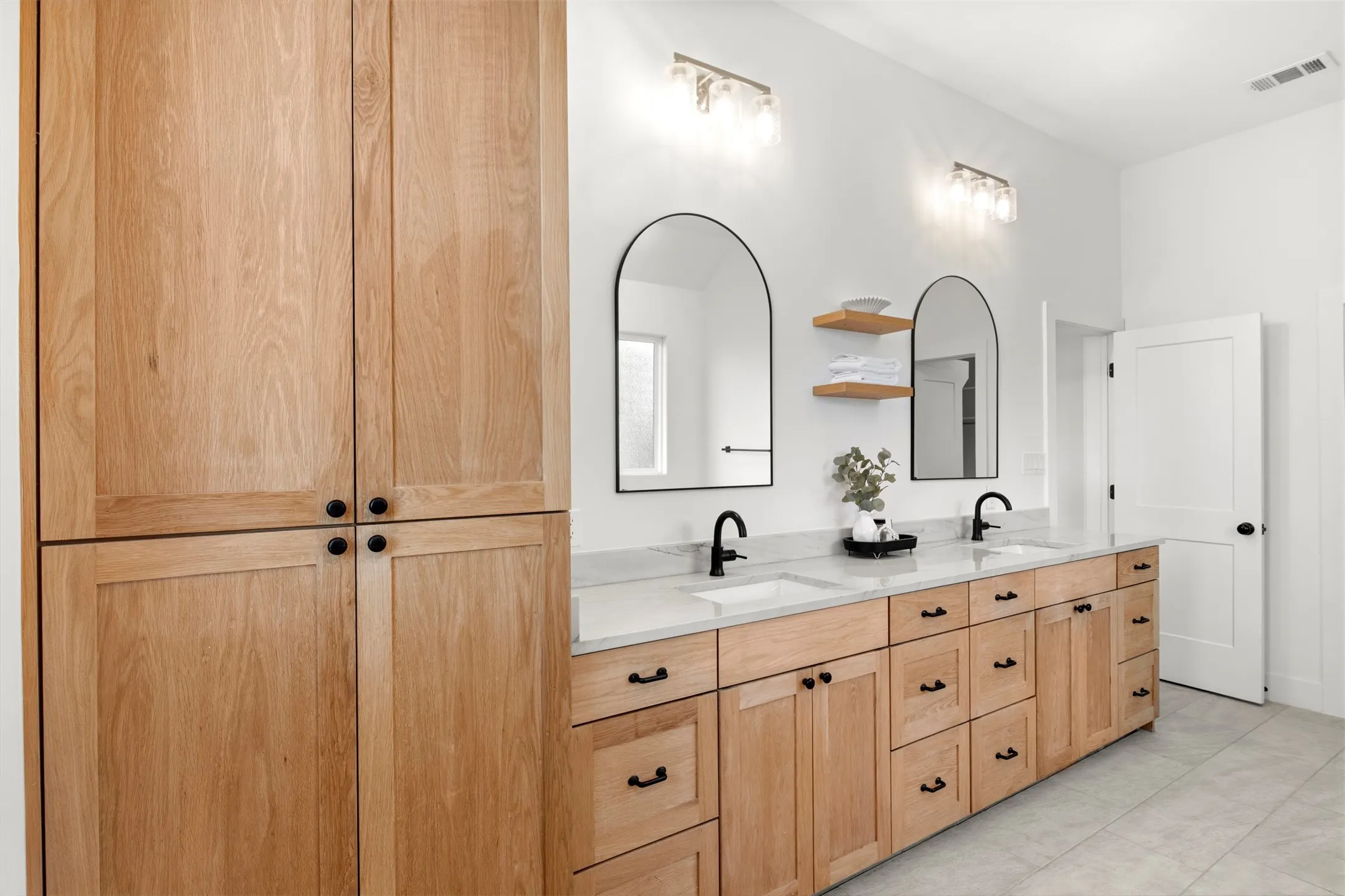 Double vanity with natural wood cabinetry, ample counter space and storage.