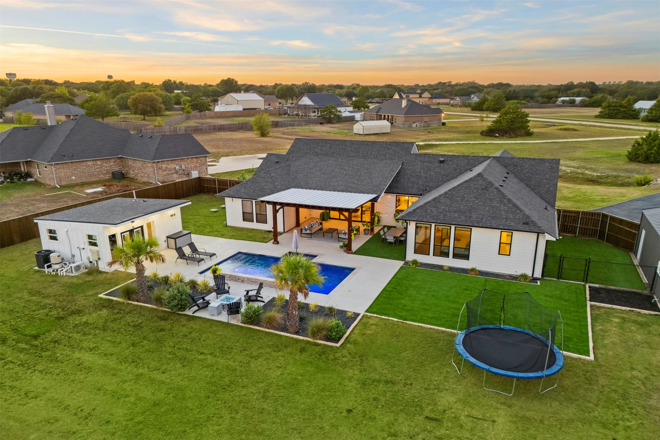 Wide backyard view highlights the home's indoor-outdoor connection and separate structures.