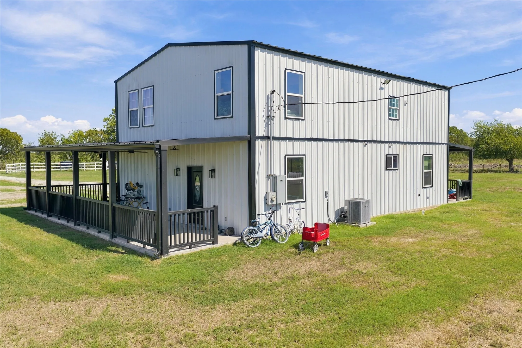 Two-story metal construction with a covered porch and railing, featuring a second-level balcony