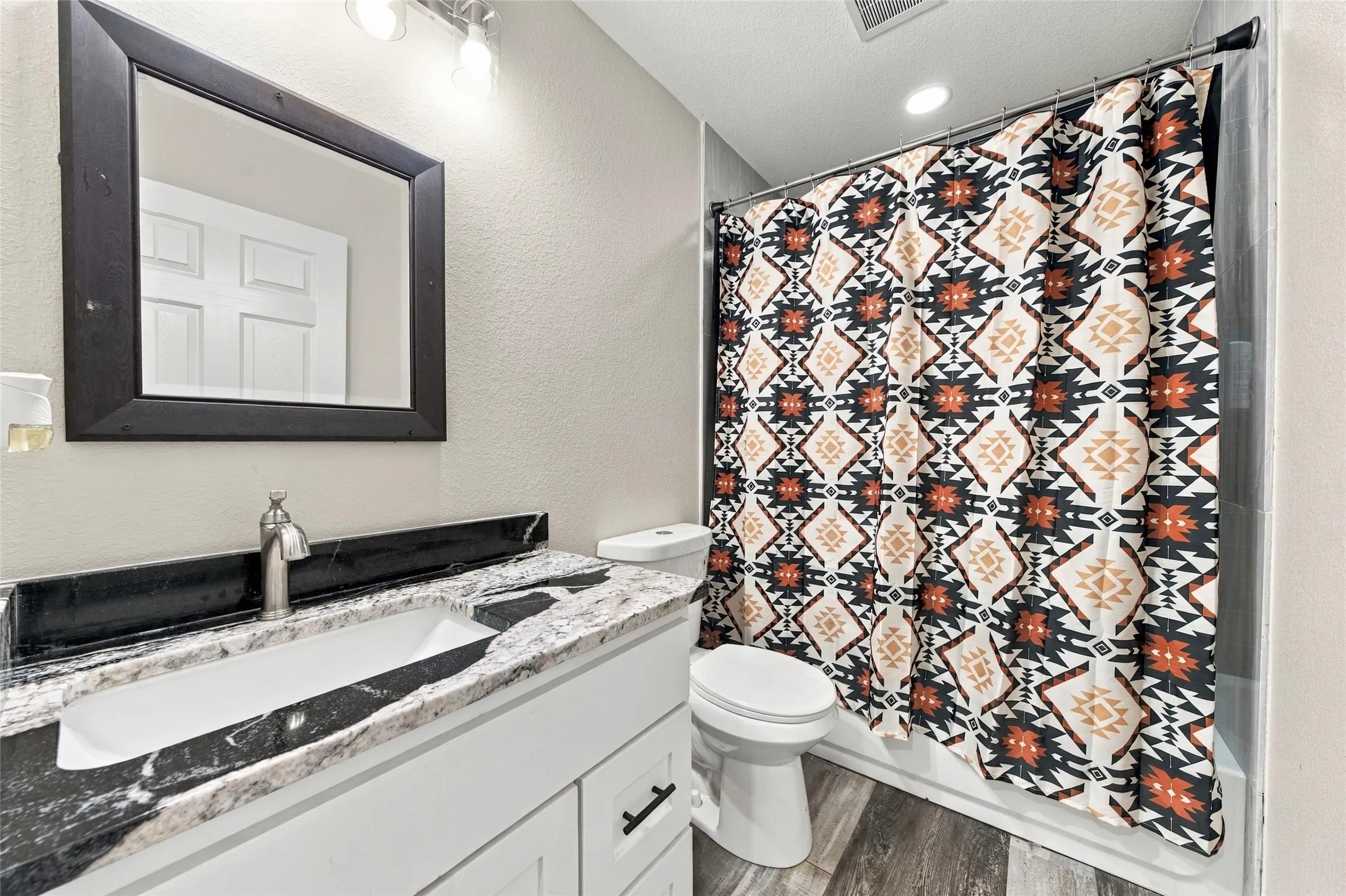 White vanity with shaker-style door fronts, a black-and-white patterned countertop, and an undermount sink