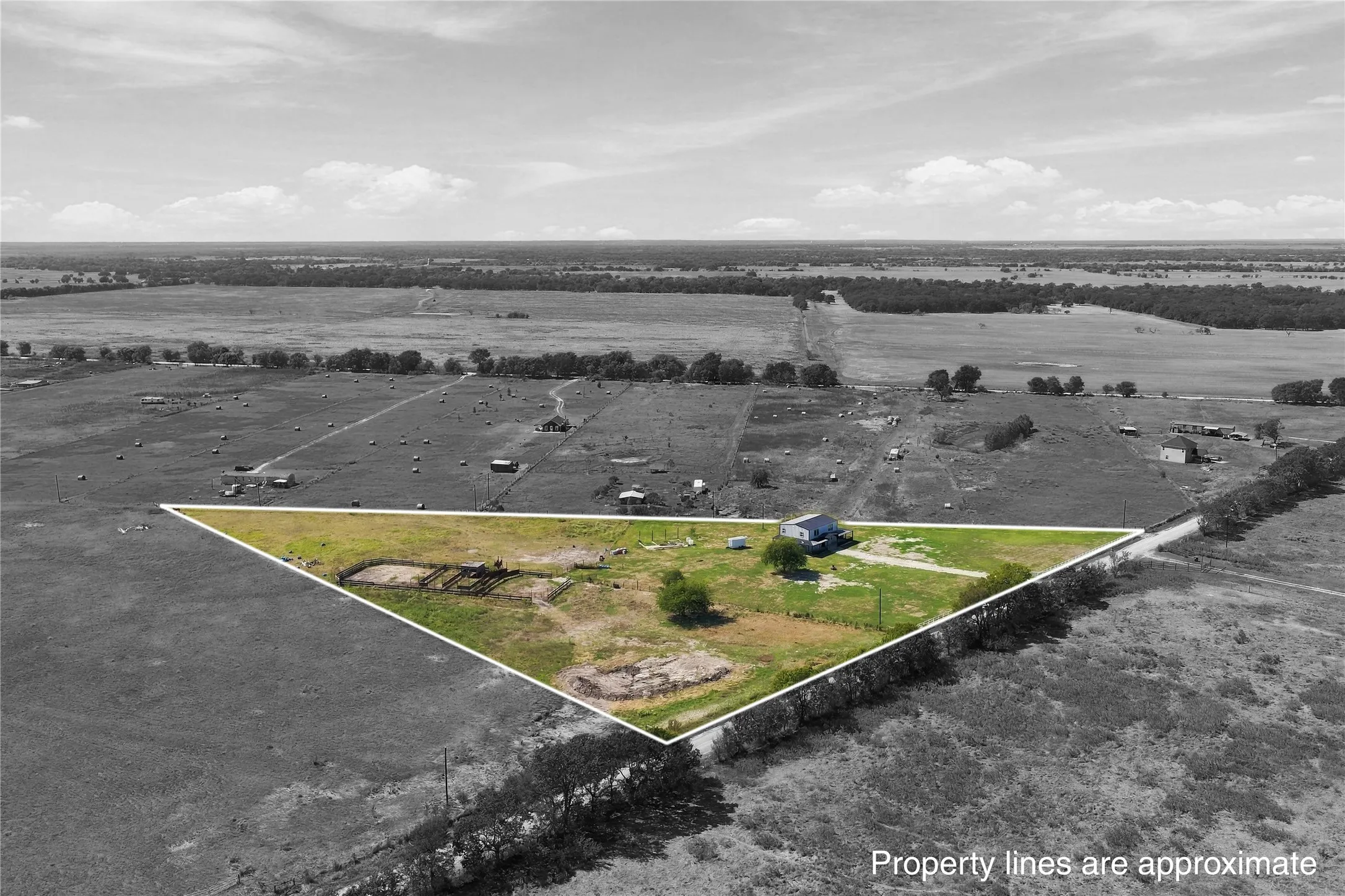 Expansive rural property featuring a singular residential structure, an undeveloped land parcel, and a distant tree line