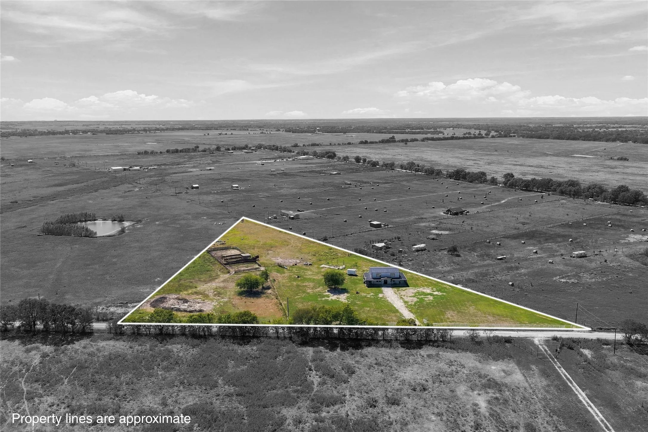 Expansive rural property featuring a residential structure, extensive pastureland, multiple outbuildings, and mature trees