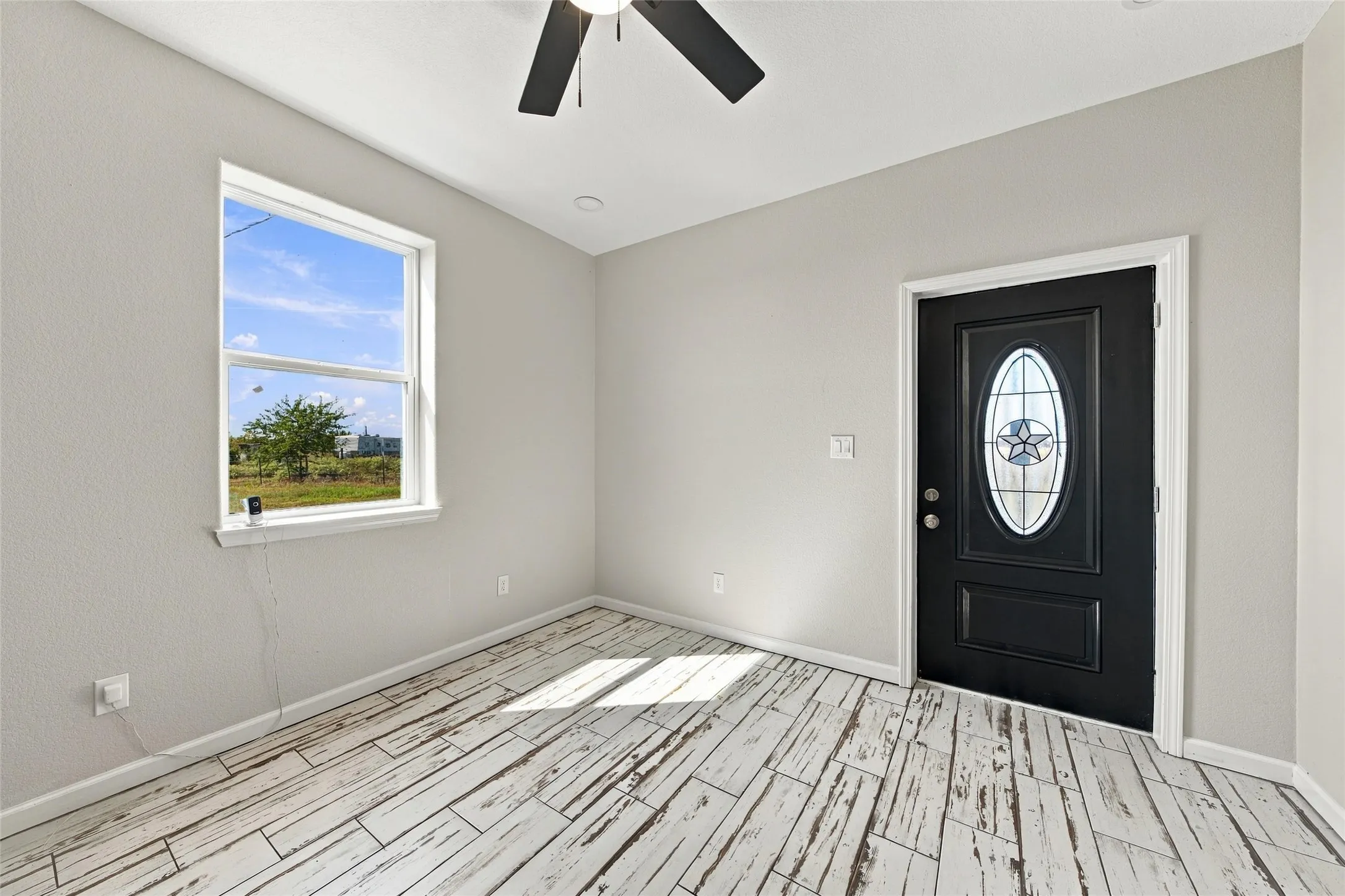 Wood-finish flooring, recessed ceiling lighting, a dark-paneled door with an oval stained-glass insert, and a ceiling fan