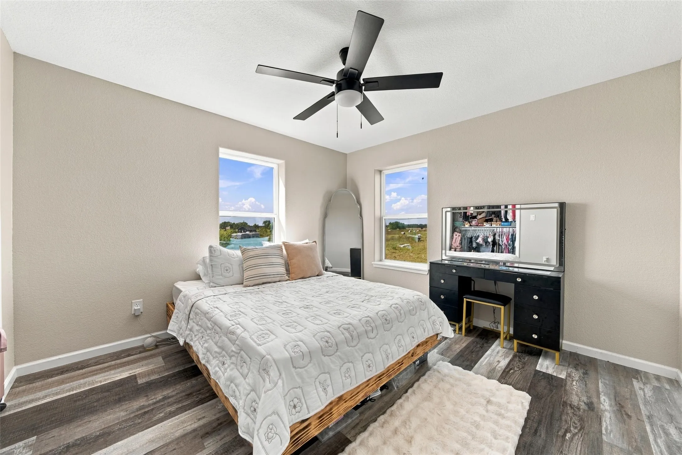 Wood-finish flooring, two windows, and a ceiling fan with light fixture