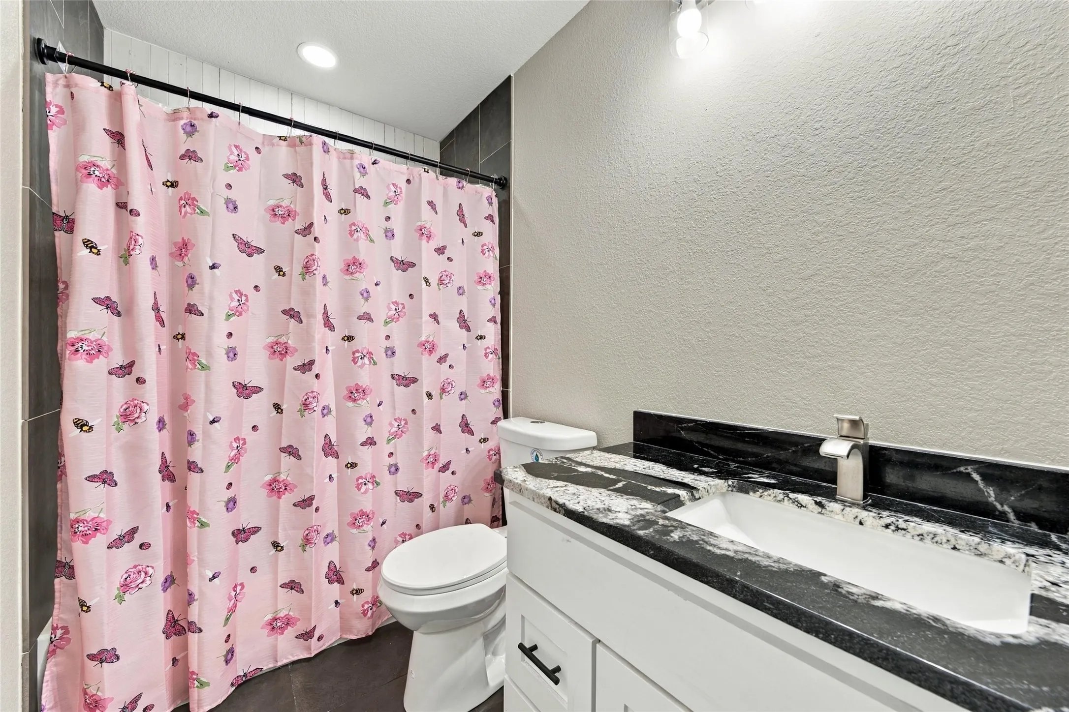 Vanity with integrated sink, black and white countertop, and brushed nickel faucet
