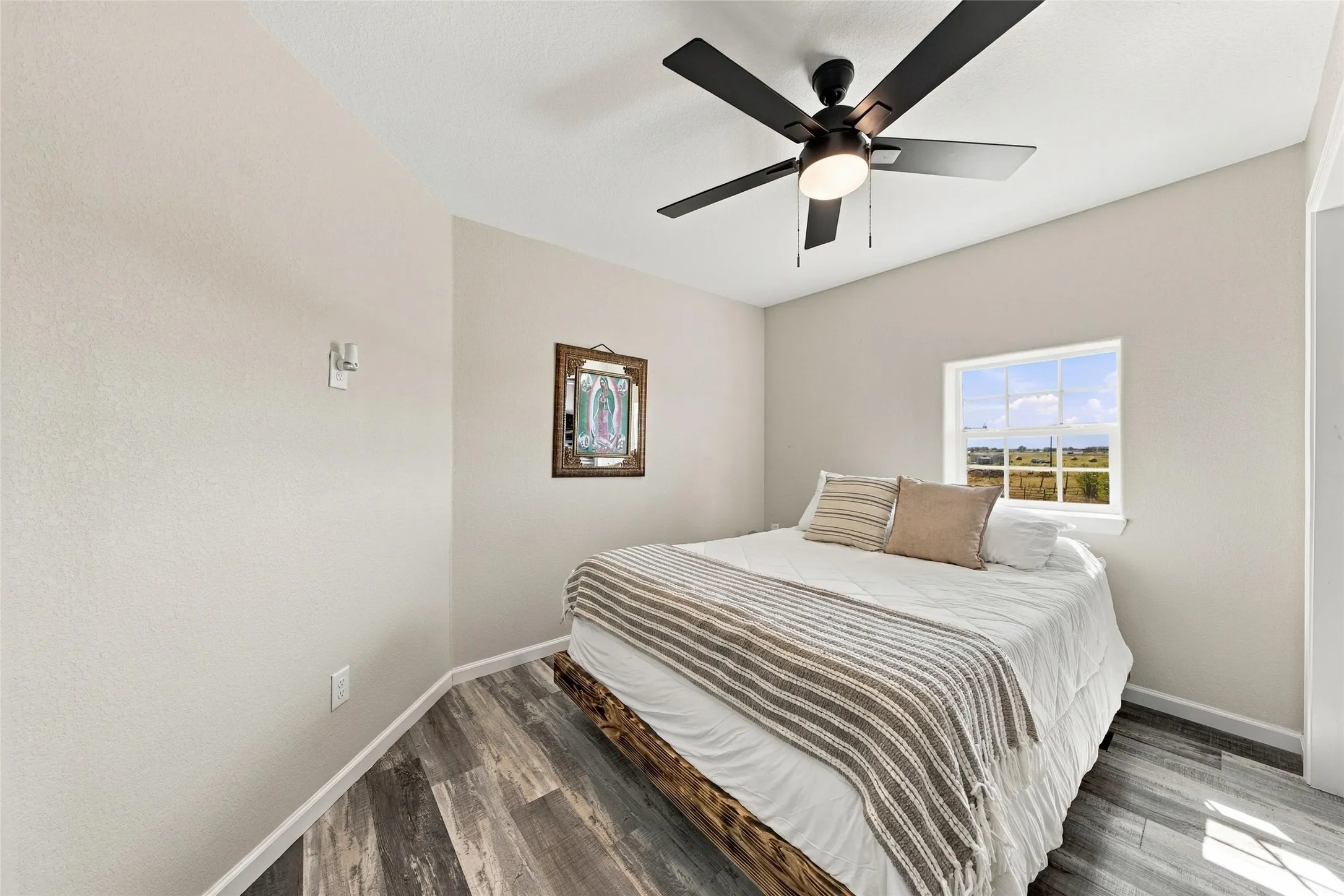 Wood-finish flooring, neutral wall tones, transom window, and a black ceiling fan with light fixture