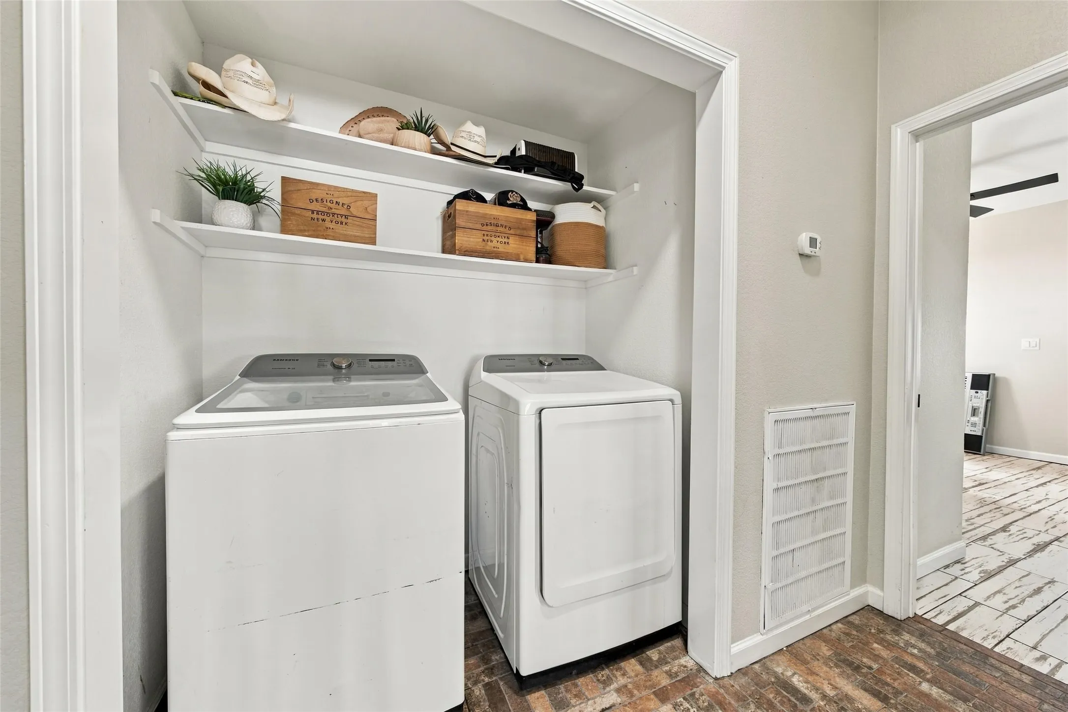 Dedicated laundry alcove featuring overhead shelving and wood-finish flooring