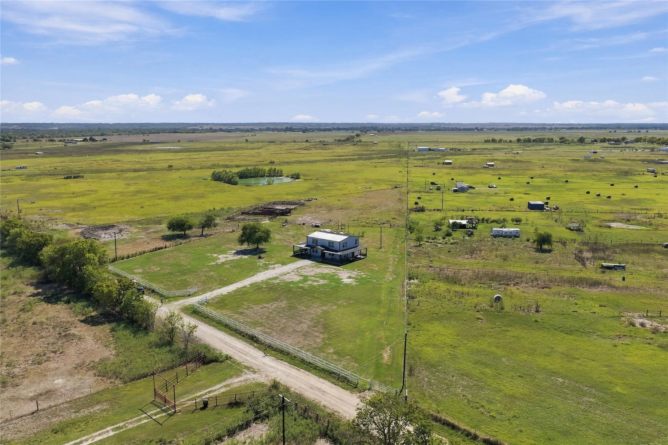 Expansive property featuring a residence, a pond, and surrounding open fields