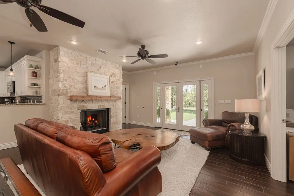 Stone-clad fireplace with a wood mantle, recessed lighting, ceiling fans, and wood-finish flooring