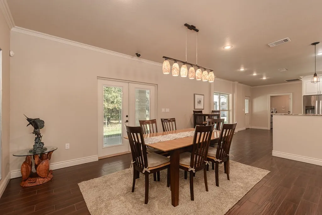 Living area featuring a stone fireplace with a wood mantle, wood-finish flooring, and crown molding