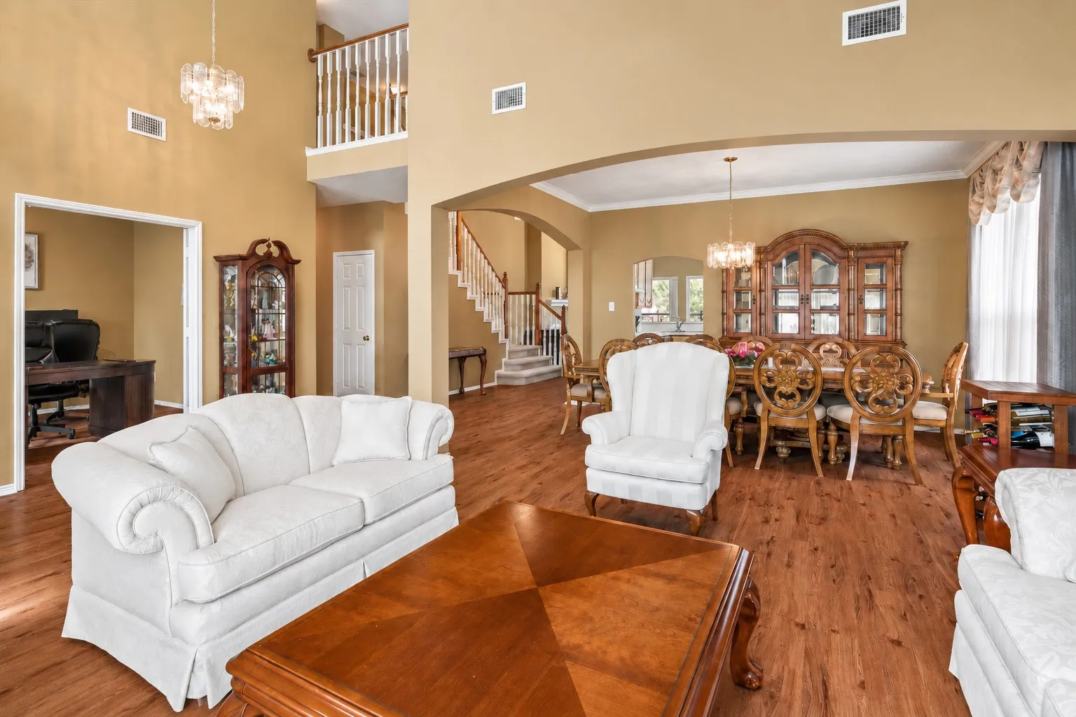 Two-story living area with wood-finish flooring, arched entryways, and a chandelier