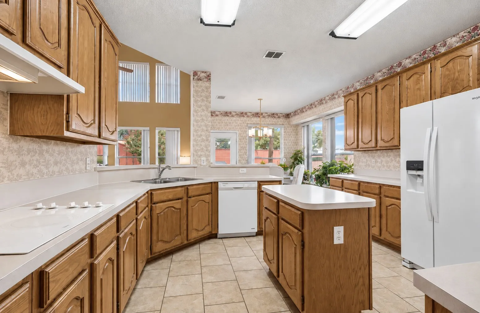 Kitchen with wood cabinetry, white countertops, a built-in cooktop, and a center island