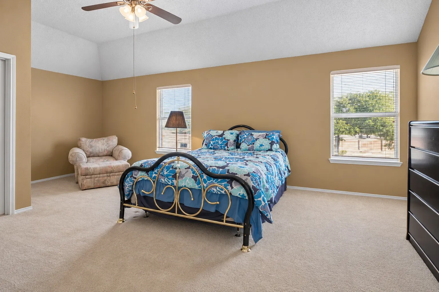 Vaulted ceiling with an attached ceiling fan, two windows with blinds, and neutral carpet flooring