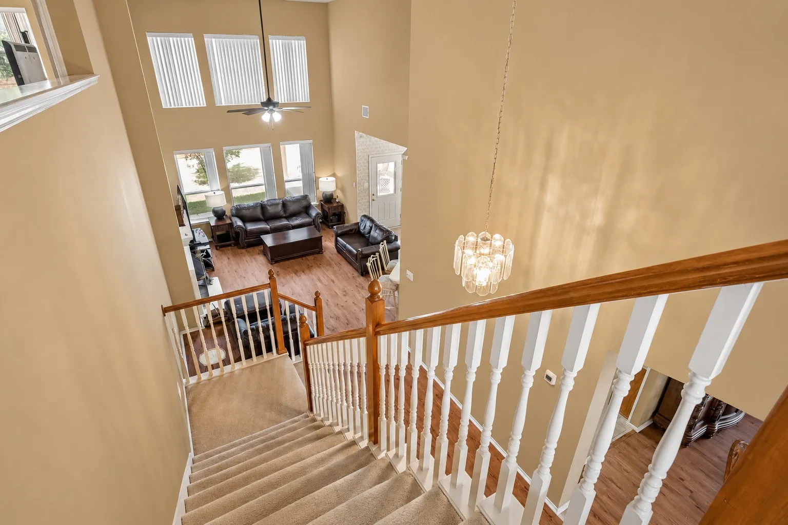 Two-story living area with high ceilings, multiple large windows, and wood-finish flooring