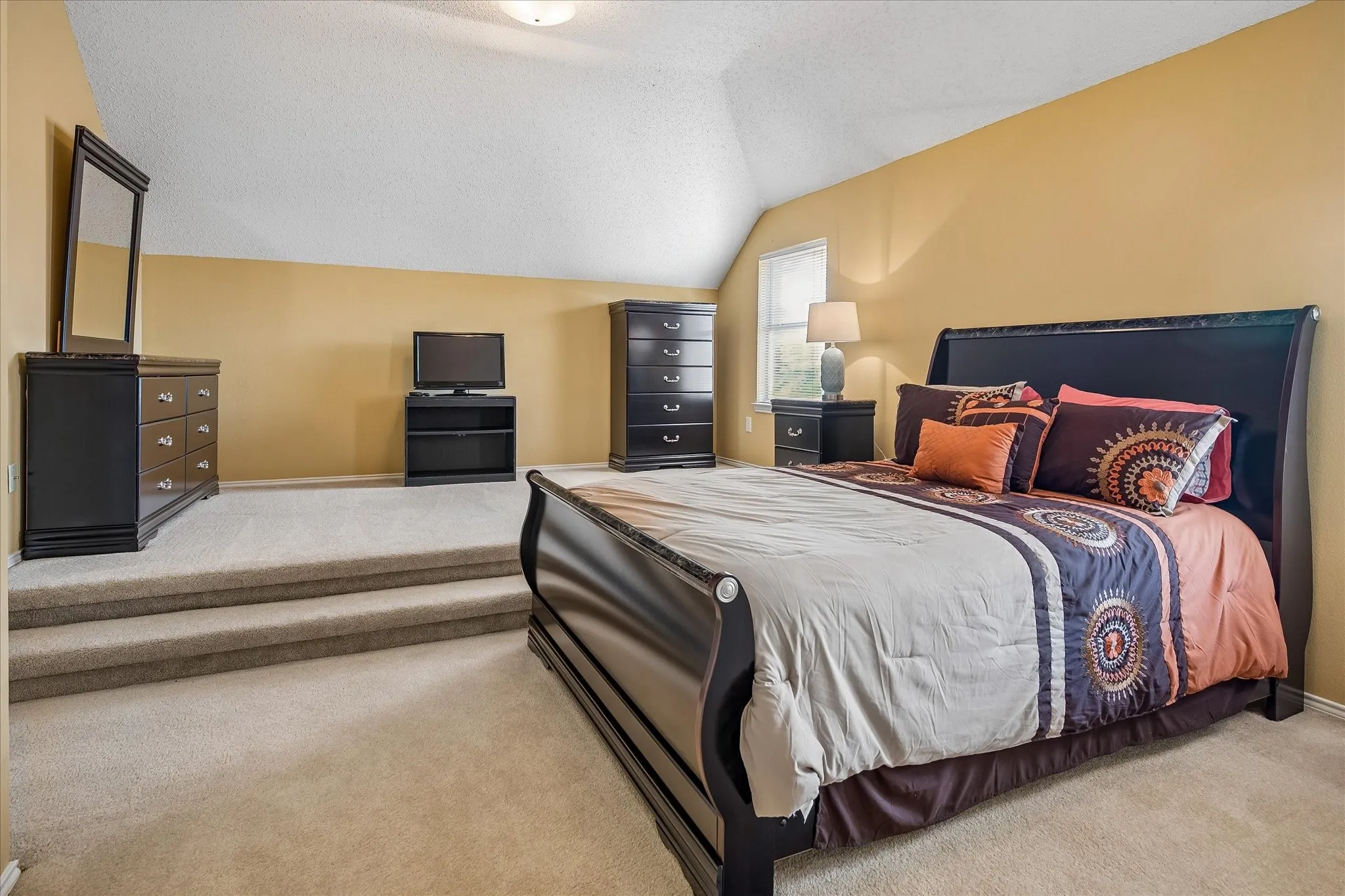 Room featuring a split-level floor design, wall-to-wall carpeting, vaulted ceiling, and recessed window