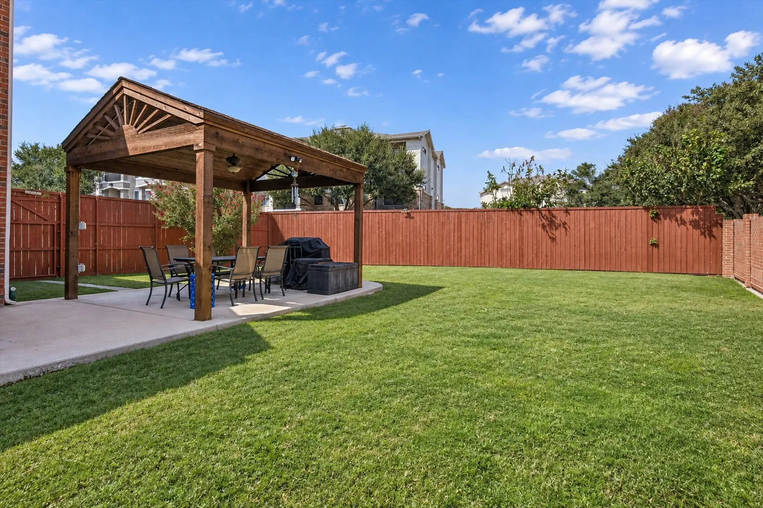 Expansive backyard featuring a manicured lawn, a wood pergola over a concrete patio, and a wood privacy fence