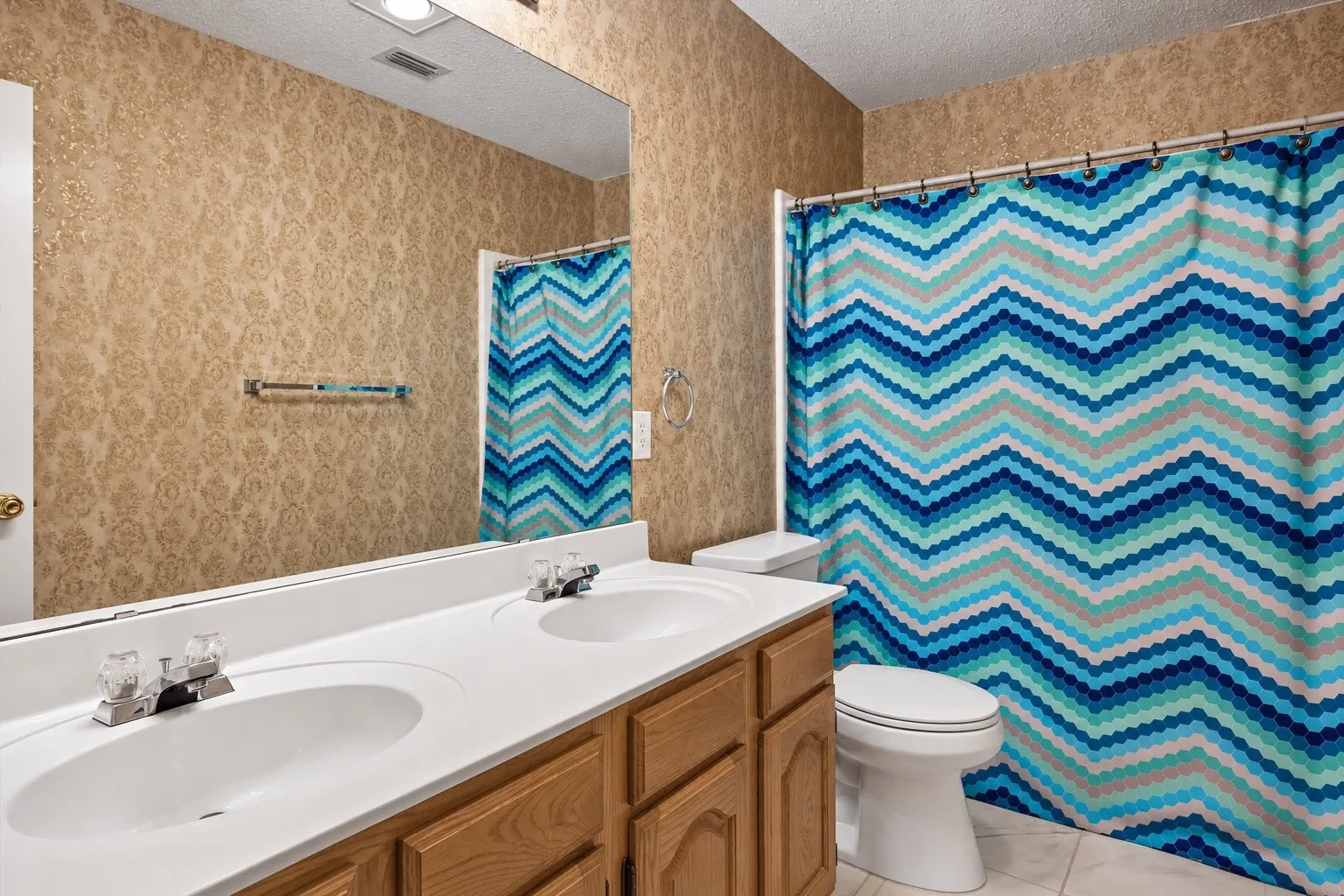 Dual vanity with integrated sinks, wood-finish cabinetry, and a full-width mirror