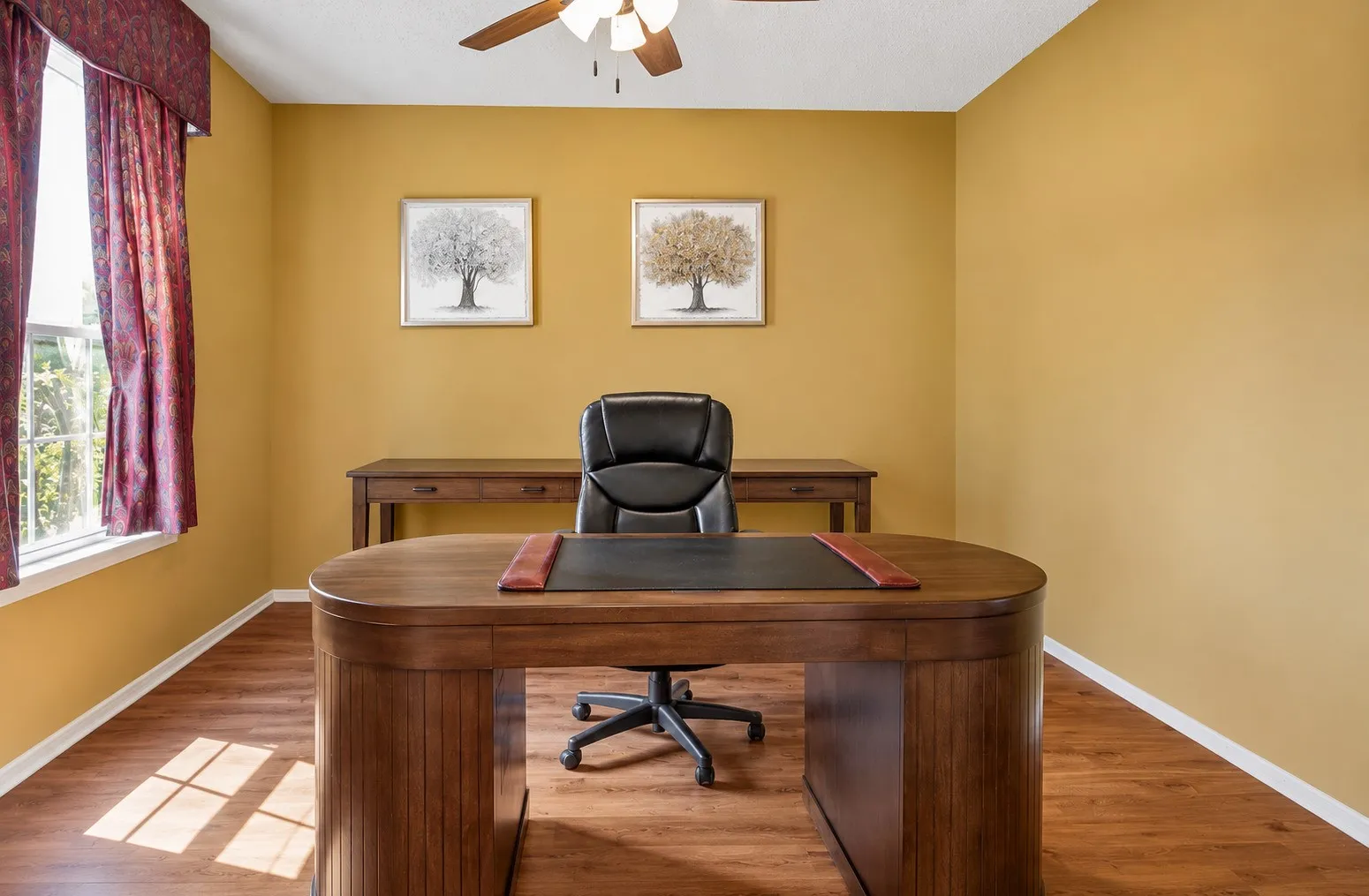 Bright room with wood-finish flooring, a ceiling fan, and a large window