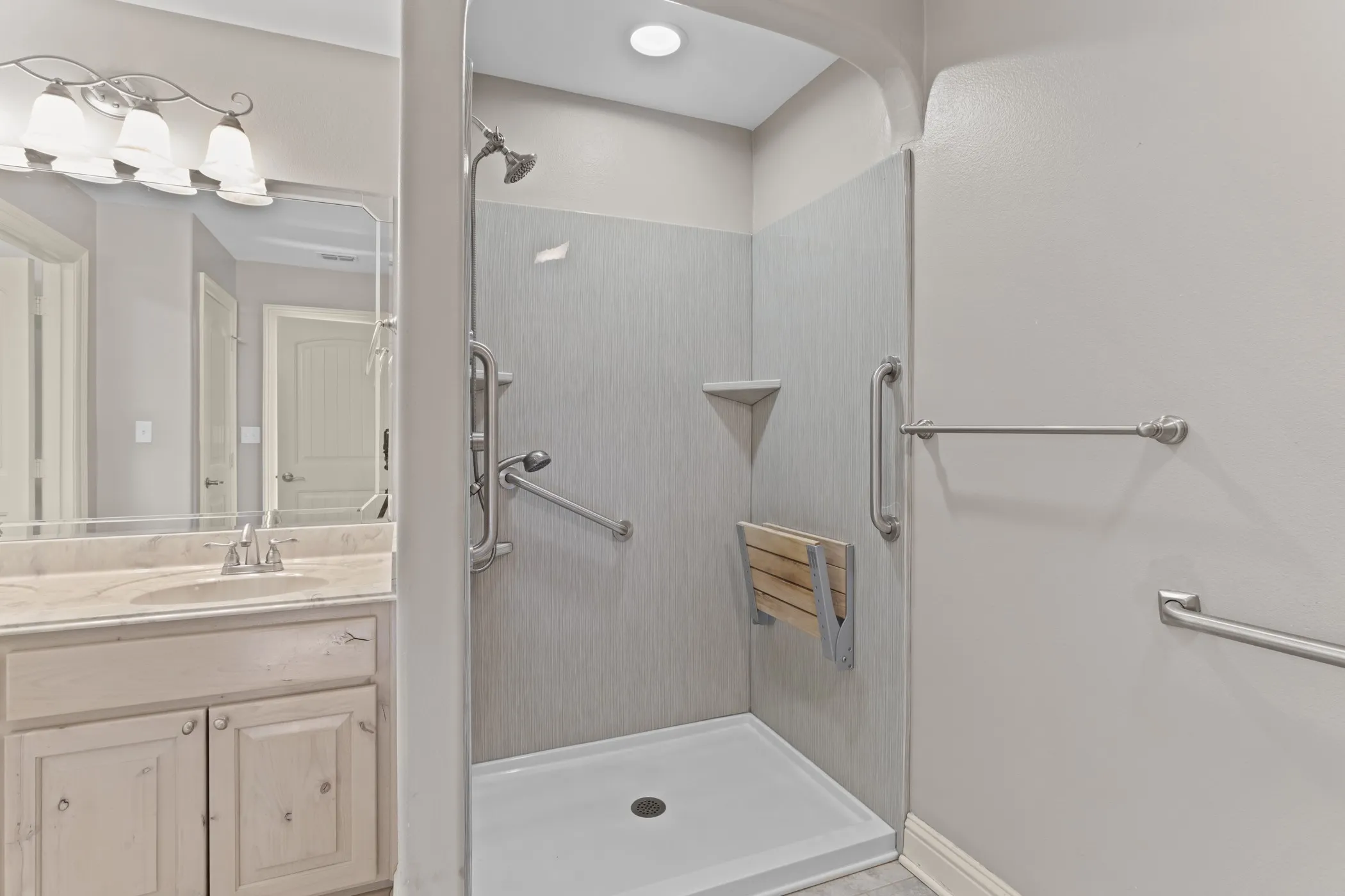 Walk-in shower with a built-in folding seat, grab bars, and a corner shelf