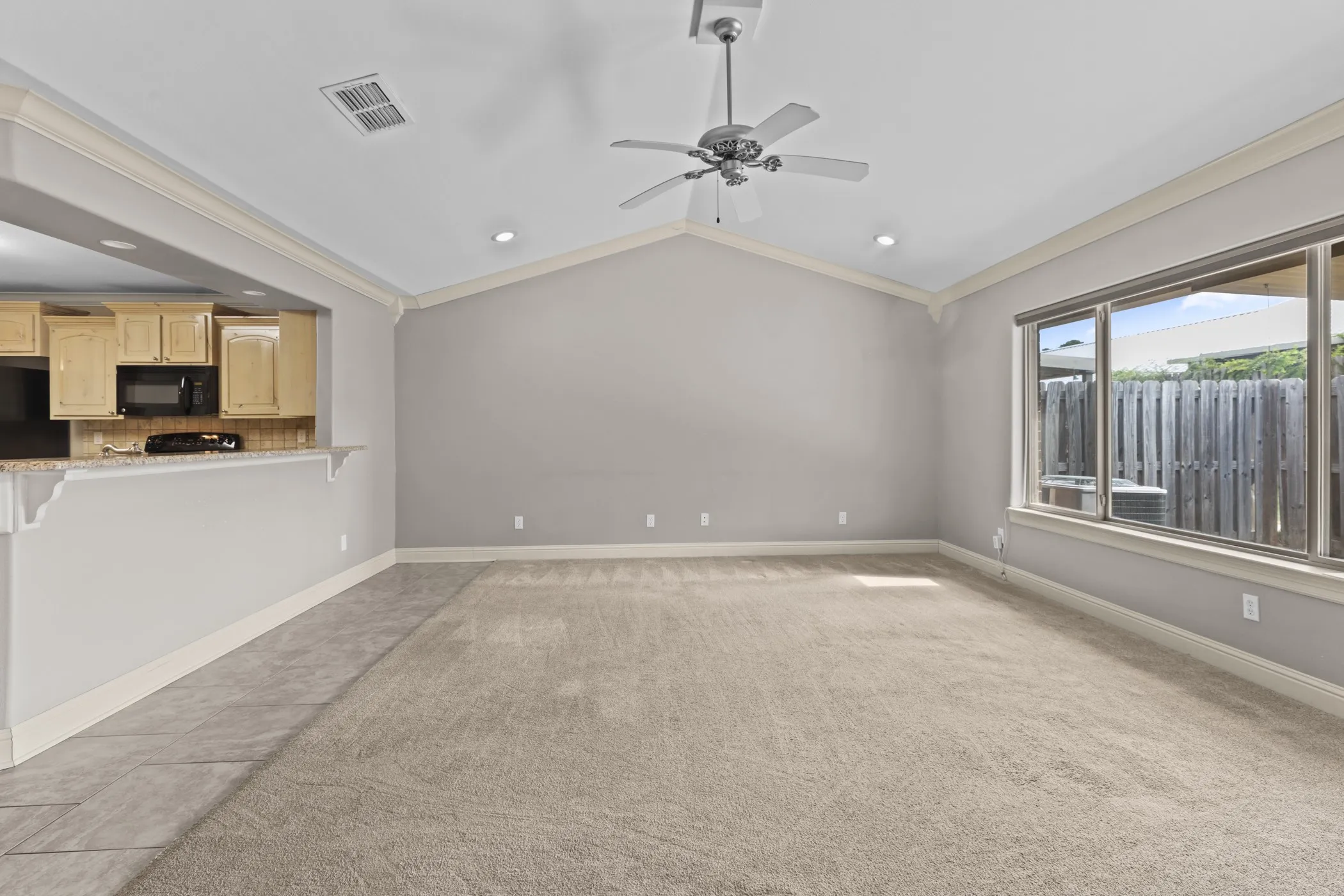 Vaulted ceiling with recessed lighting, ceiling fan, and carpeted flooring