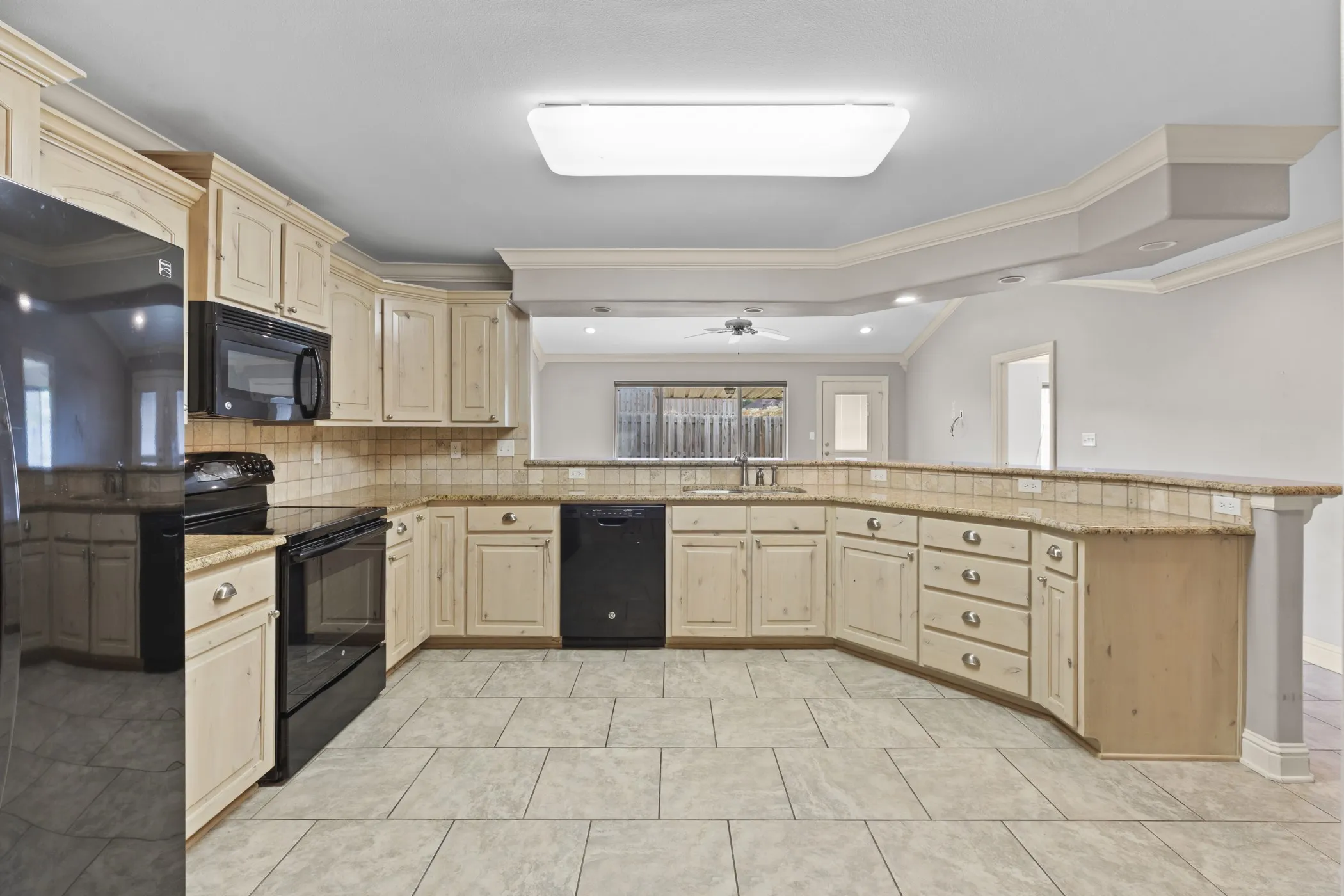 Kitchen with light-toned cabinetry, a built-in microwave, tile flooring, and a stone-finish countertop