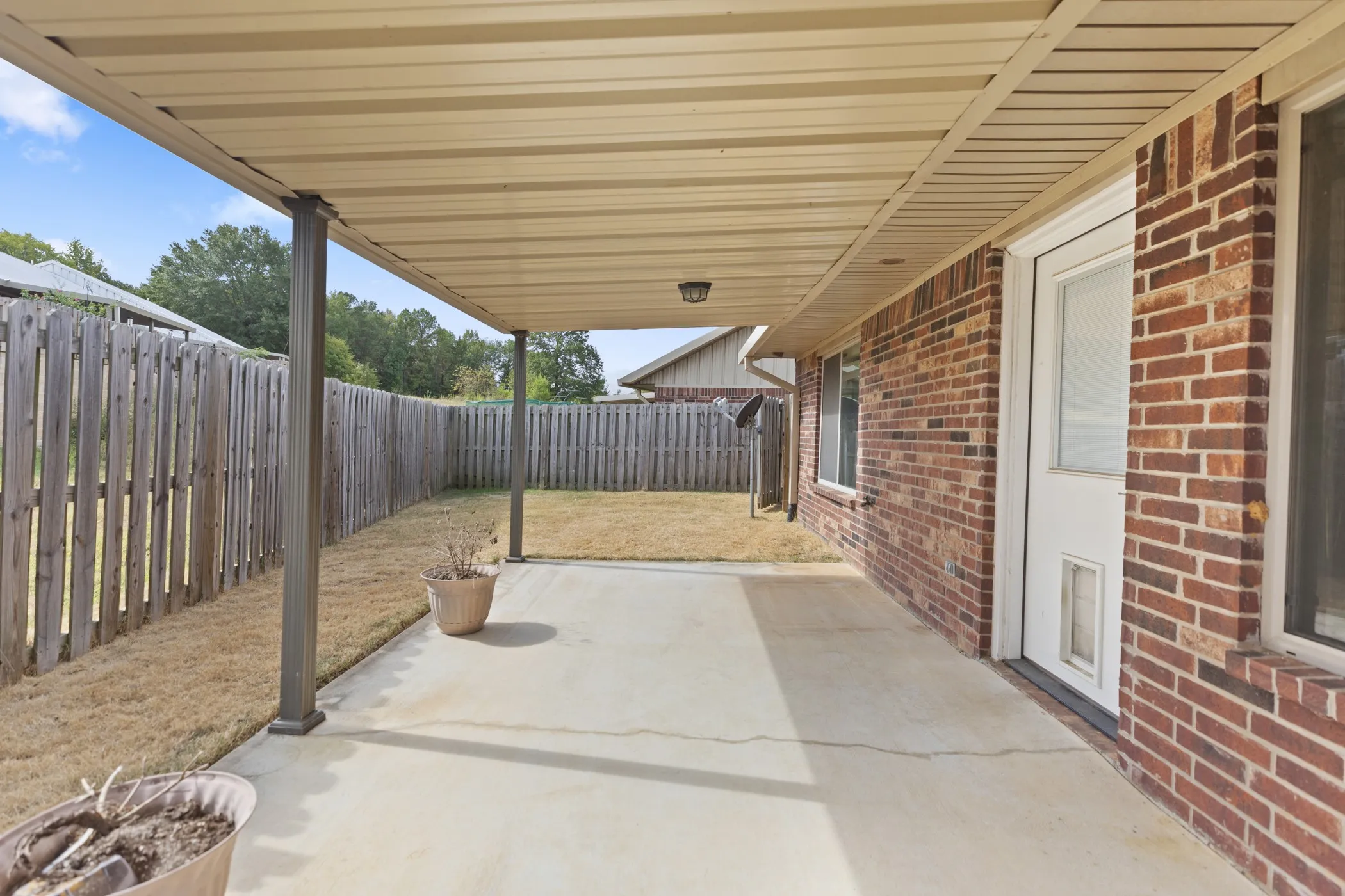 Expansive concrete patio with a covered outdoor area, supported by metal posts