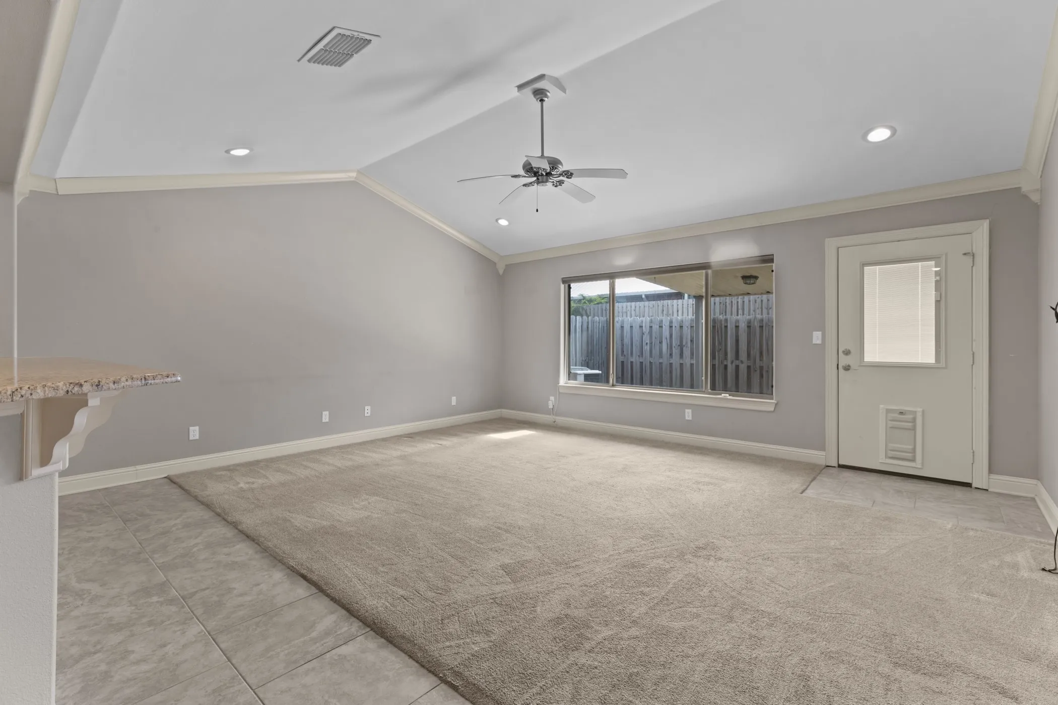 Vaulted ceiling with recessed lighting and a ceiling fan, large window, and light-toned carpeting