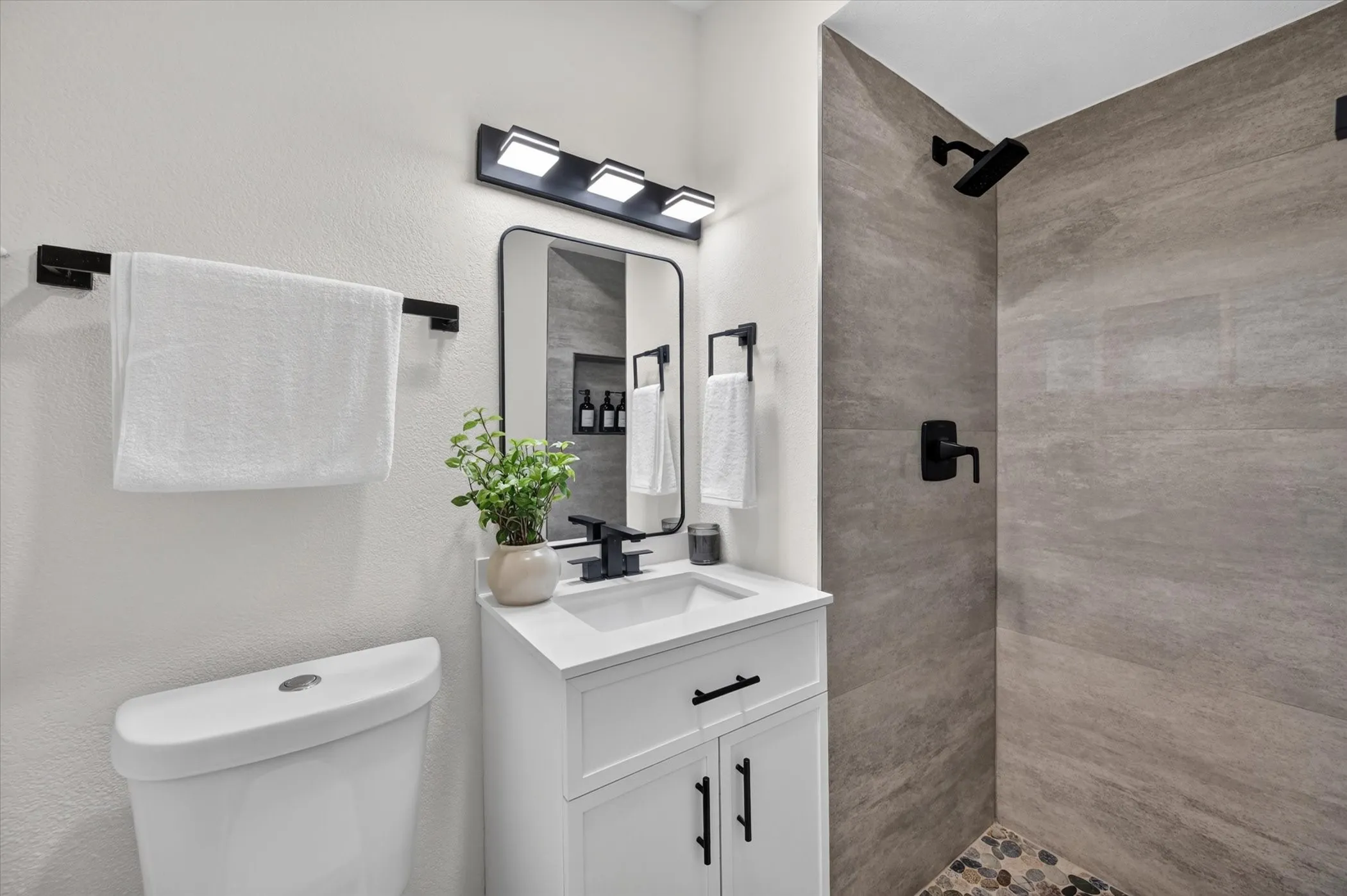 White vanity with a rectangular sink, matte black faucet, and cabinet storage