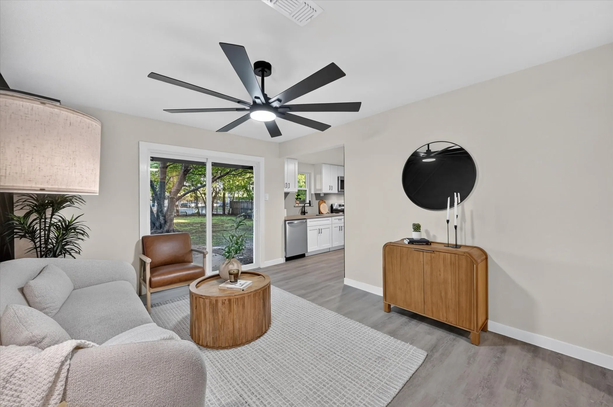 Contemporary ceiling fan with integrated lighting, wood-finish flooring, and sliding glass doors to the exterior
