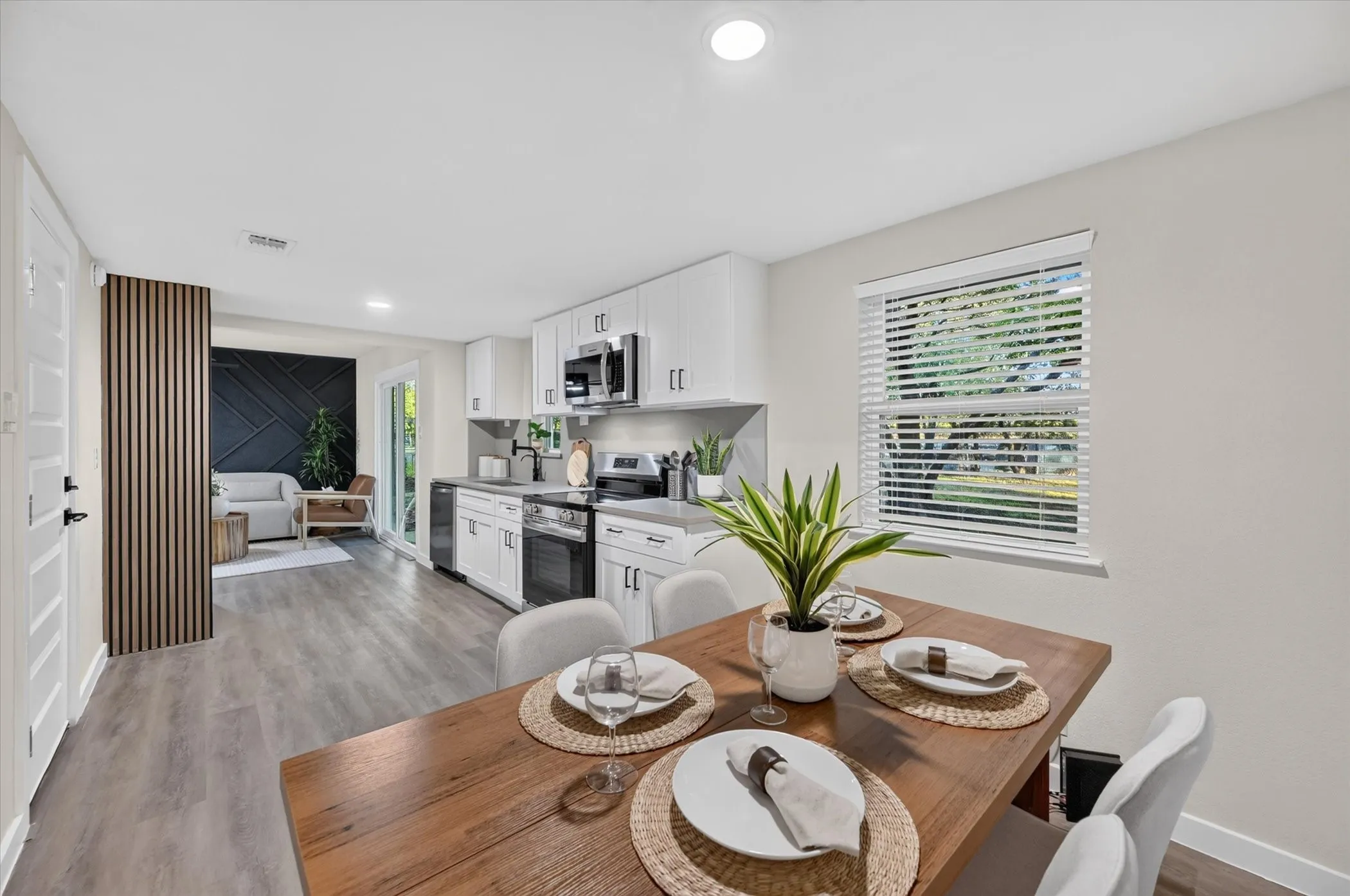 Contemporary kitchen featuring white cabinetry, stainless steel appliances, wood-finish flooring, and recessed lighting