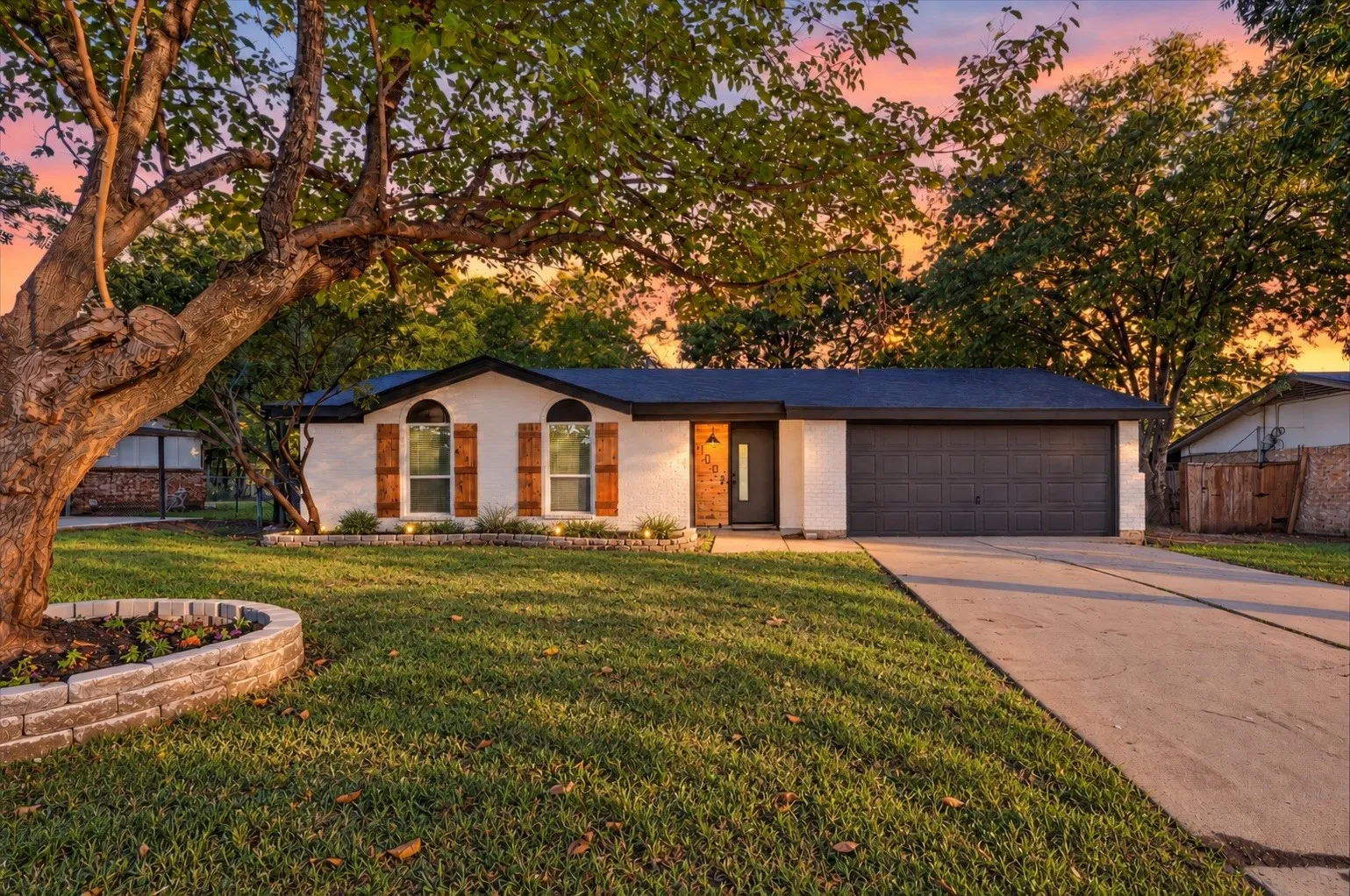 White stucco exterior with arched windows and wood-finish shutters
