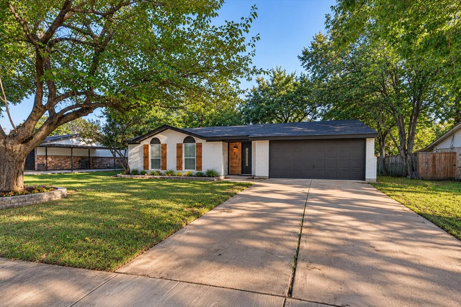 White stucco exterior with a dark shingle roof and a dark garage door