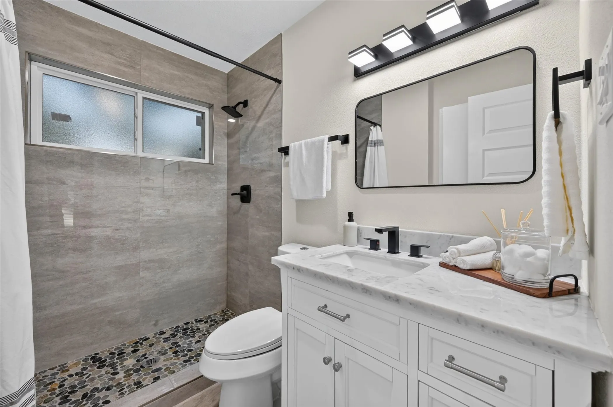 White vanity with a rectangular undermount sink, a marble-finish countertop, and matte black fixtures