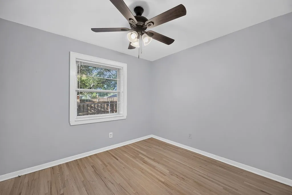 Hardwood flooring, painted walls, ceiling fan with integrated lighting, and window with blinds