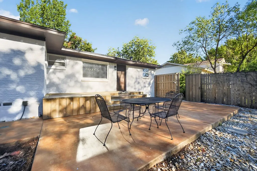 Expansive concrete patio with a detached building and wood privacy fencing
