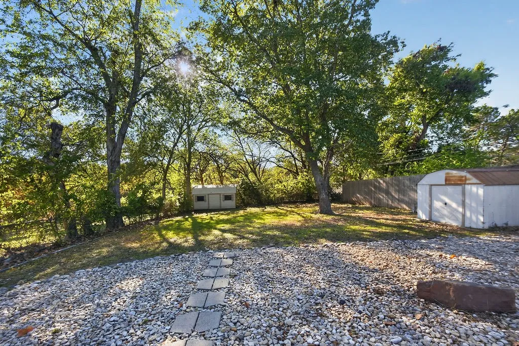 Expansive yard featuring a gravel area, concrete stepping stones, and a sloped lawn