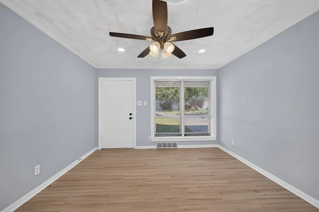 Wood-finish flooring with light blue walls, a white entry door, and a multi-pane window