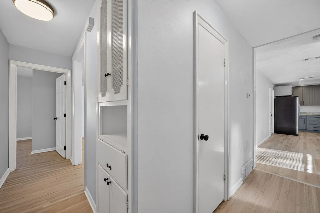 Wood-finish flooring, built-in storage cabinetry, interior doors with black hardware, and an overhead light fixture