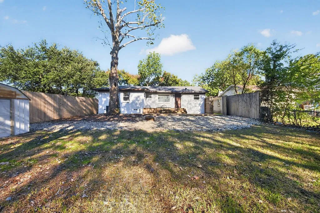 Expansive backyard featuring a manicured lawn, established tree, and a wooden privacy fence