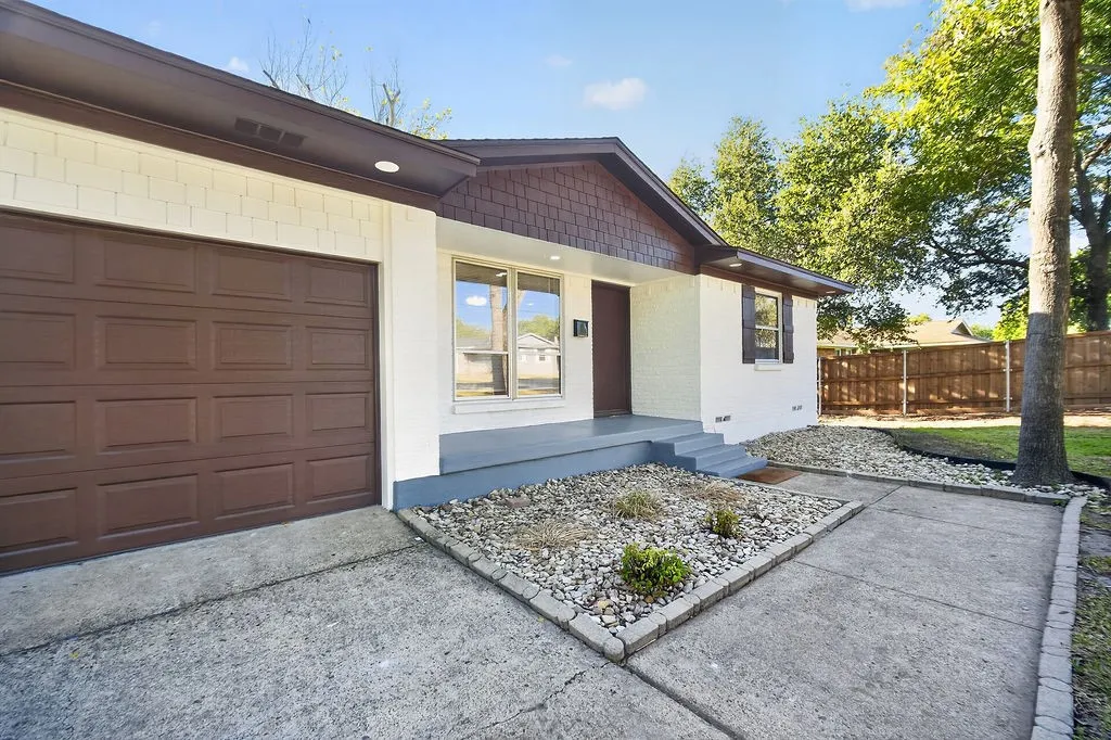 White brick exterior with a brown garage door, front entry porch, and partial shingle siding