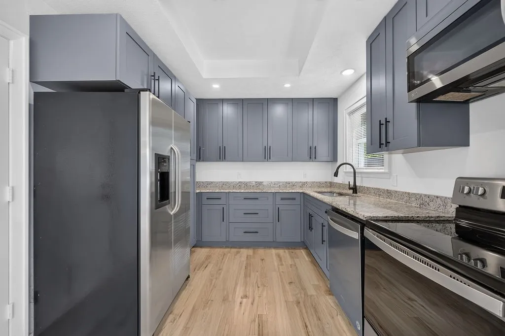 Kitchen featuring U-shaped cabinetry, granite-finish countertops, stainless steel appliances, wood-finish flooring, and recessed lighting
