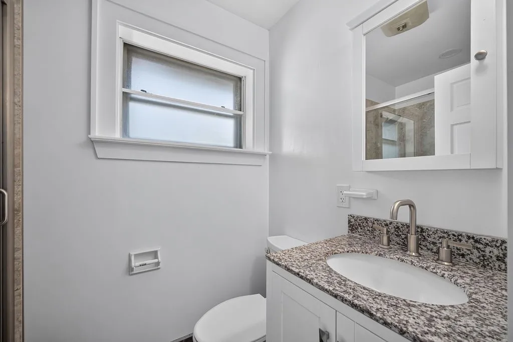 Bathroom featuring a white vanity with a speckled countertop, undermount sink, and brushed nickel fixtures