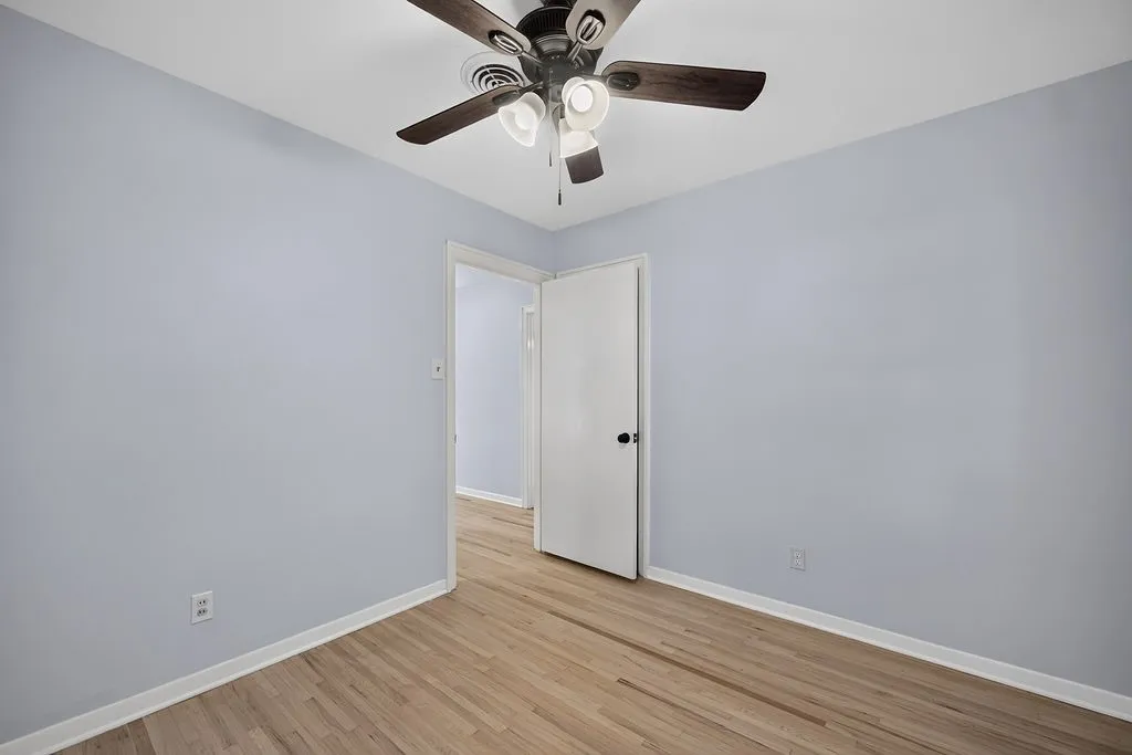 Wood-finish flooring, light-toned walls, and a ceiling fan with integrated lighting