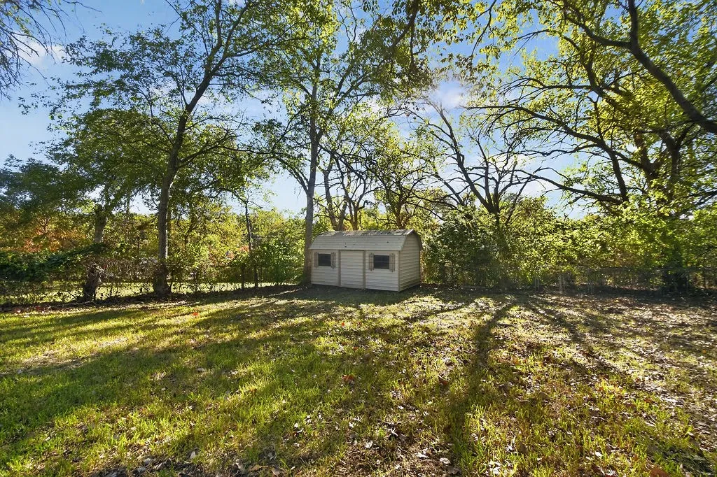 Expansive lawn with mature trees and a detached shed