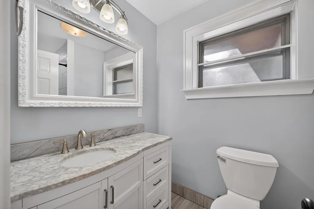 White shaker vanity with a stone countertop, undermount sink, and brushed nickel faucet