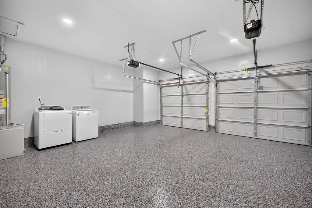 Dual garage doors with automatic openers, speckled epoxy flooring, and recessed ceiling lighting
